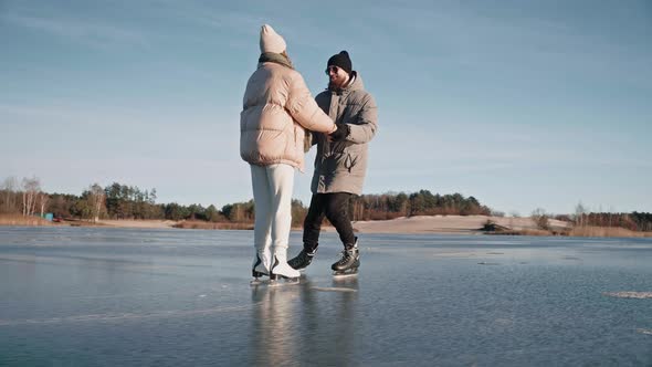 Man Teaching Woman How to Ice Skate on a Frozen Lake on a Sunny Winter Day