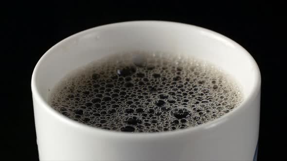 White bubbles beautifully burst in a cup with coffee slow motion.