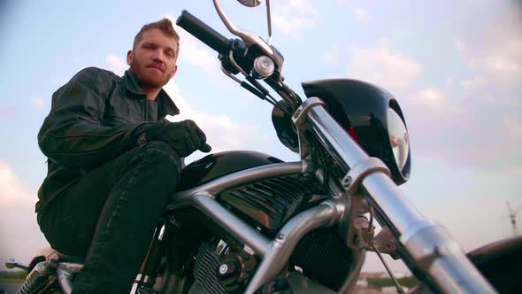 Young Man Sitting on Motorcycle on the Road at Sunset Slow Motion