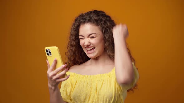 Young Woman Using Smartphone Against Yellow Background