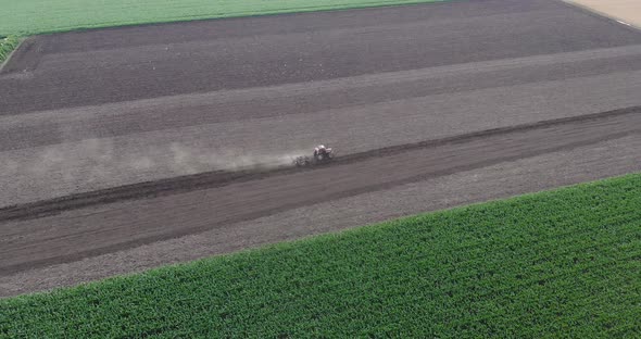 Agricultural Tractor Plowing The Fields With Ripe Wheat Crops In The Distance alt
