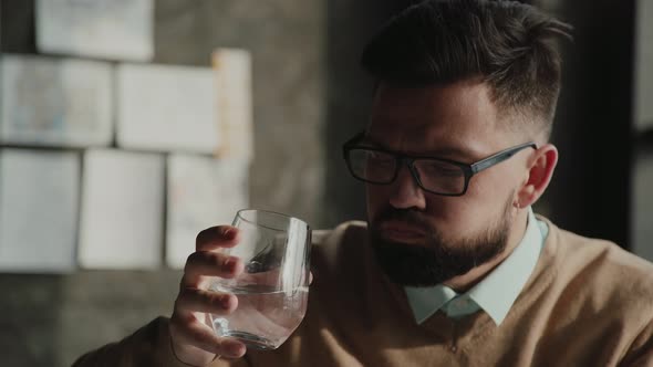 Man Holds White Pills and a Glass of Water. Businessman Takes Pills