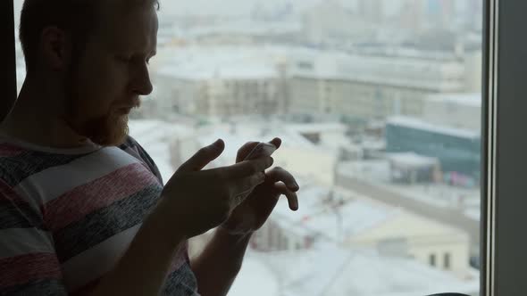 silhouette of a man with a smartphone at the window overlooking the city