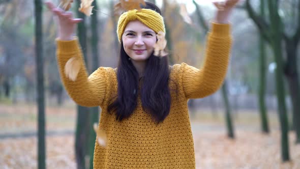 A Young Girl Throws Leaves in an Autumn Park alt