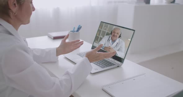 Online Consultation of Two Medical Specialists By Video Calling on Laptops, Woman Is Looking at Male alt