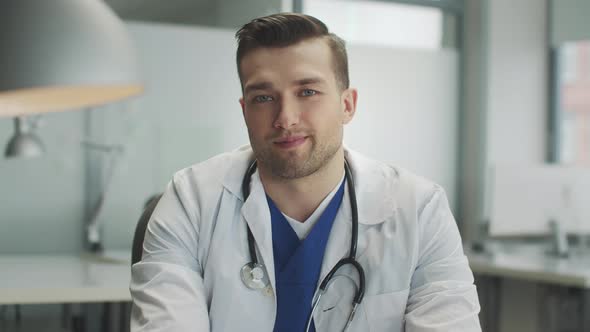 An Attractive Male Doctor in His Office Adjusts the Stethoscope on His Neck Slow Motion alt