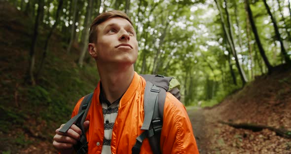 Man with Backpack Looking Around in Forest