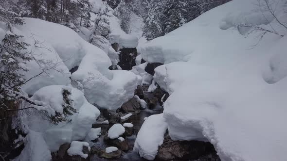 winter wonderland in the alps. A small valley with a snowy creek, Kleinwalsertal, Austria. Drone fly alt