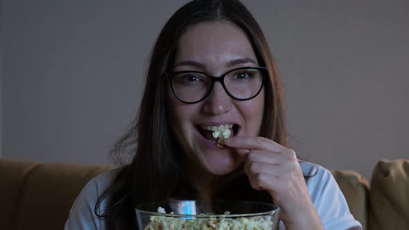 Woman in Glasses Eats Popcorn and Watches Television alt