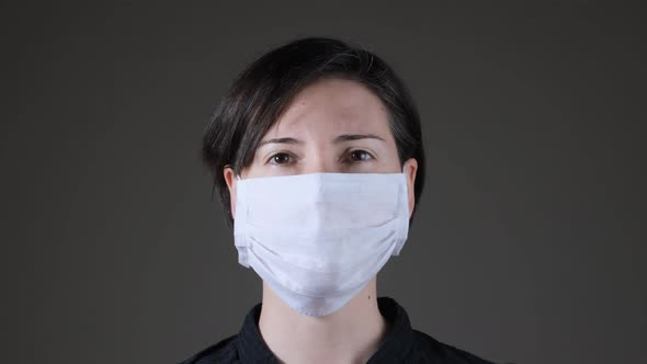 Portrait of a Caucasian woman wearing and taking off a white medical mask