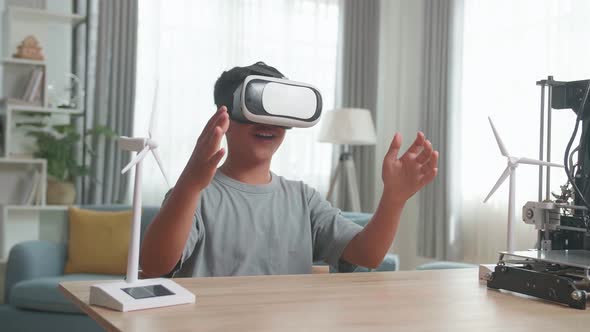 Asian Boy Wearing VR Glasses While Experimenting With Wind Turbine Model At Home alt