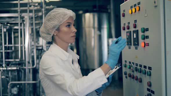 Female Worker Is Operating a Control Panel in a Factory Unit alt