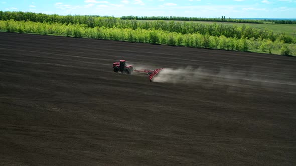 Tractor Processes the Land for Seeding, Dust Flies. Agricultural Work for Sowing Grain. Side View