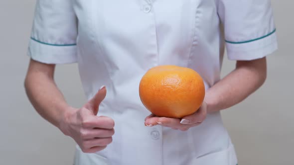 Nutritionist Doctor Healthy Lifestyle Concept - Holding Grapefruit and Medicine or Vitamin Pill alt