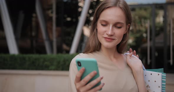 Close Up View of Pretty Girl Using Her Smartphone While Standing at Street. Beautiful Millennial alt