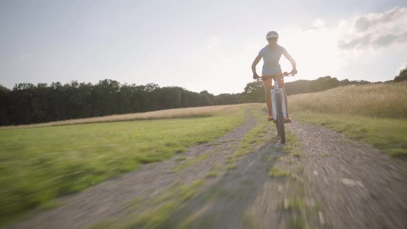 Woman on  Mountain Bike Following Camera in Rural Landscape in Summer