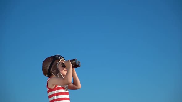 Happy child looking through vintage binoculars against blue sky