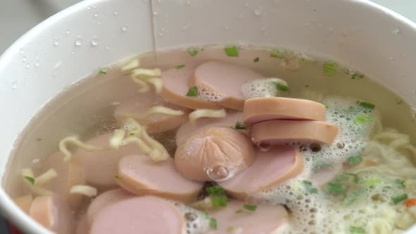 Sliced Sausages Falling Into Brewed Instant Noodles Asian Sweet and Sour Noodles alt