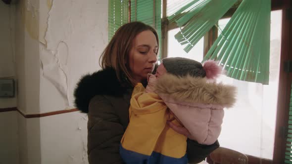 Troubled Ukranian migrant consoling her crying daughter during Russia war