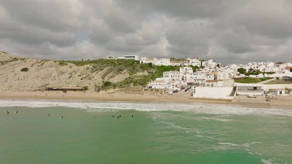 Aerial shot of surfers outside a small coastal town waiting to catch waves alt
