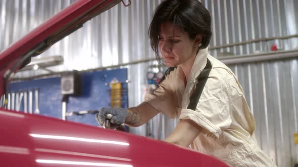 Woman Mechanic with Tattoos Repair Car with Tools in Car Service alt