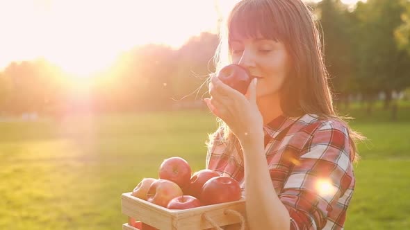 Beautiful young woman in casual clothes inhales the aroma of a ripe fresh apple