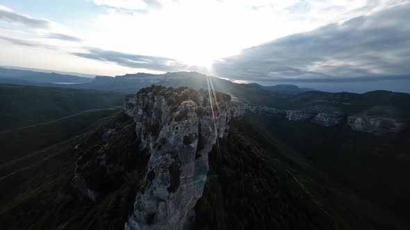 Dynamic Drone Shot Along Rocky Mountain Cliff and Towards to Beautiful Sunset