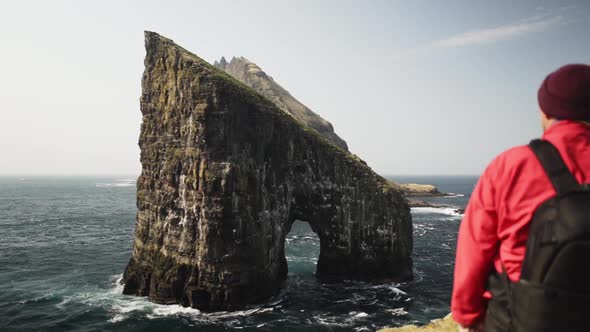 Drangarnir Rock and Birds Flying Around It in Middle of Deep Blue Ocean Water alt