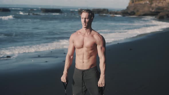 Close Up Front View of Perfect Body Sportsman Trains Arms with Elastic Band alt