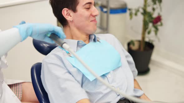 Young Smiling Male Patient Rinsing Mouth During Dental Treatment in Clinic alt
