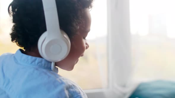 African Boy Sitting on Bed and Enjoying Music on Smartphone