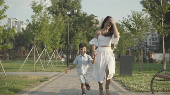 Cheerful Mother Son Running Along Sunny Alley Summer Park alt