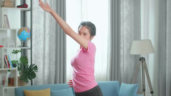 Asian Fit Beautiful Girl In A Pink Athletic Outfit Is Energetically Exercising In Her Living Room alt