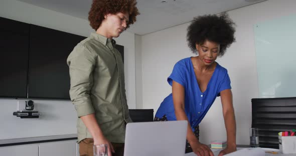 Diverse male and female business colleagues in discussion at work looking at technical drawing alt