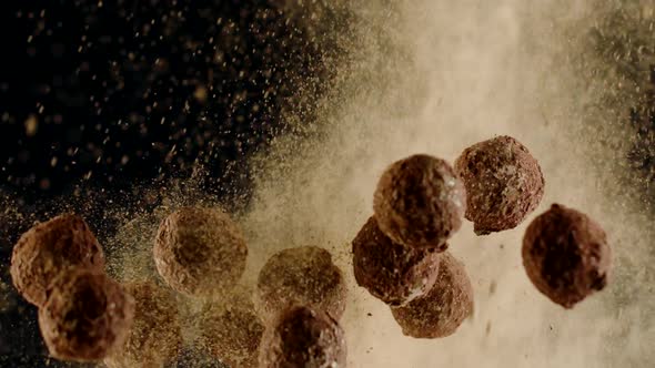 Dark Chocolate Truffles Flying Up Colliding with Cloud of Cocoa Powder, Close-up