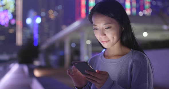 Woman look at smart phone in the city at night alt