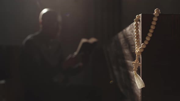 Rosary Beads and Clergyman Reading Bible on Background alt