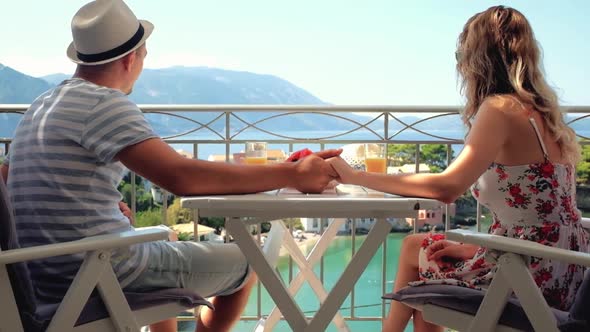 Happy family have a breakfast sitting on balcony at beautiful island background