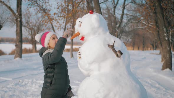 Girl Inserts a Nose on the Snowman alt