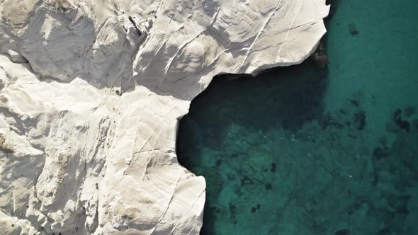 Bright white rocky cliffs cast a shadow into the crystal-clear waters of the Mediterranean Sea. Summ alt