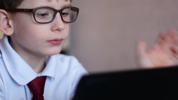 caucasian boy 7-8 years old wearing glasses is studying science sitting at the table holding a gadge, Stock Footage 