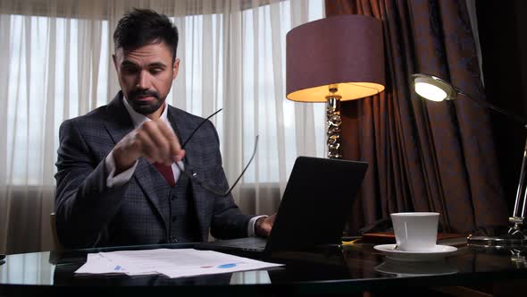 Tired Man in Eyeglasses Working at Desk in Office alt