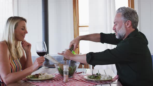 Happy caucasian mature couple smiling, talking and enjoying meal together alt