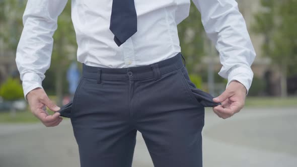 Unrecognizable Bankrupt Businessman Showing Empty Pockets Outdoors. Insolvent Caucasian Man Having alt