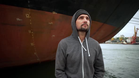 in Slow Motion Dreaming Relaxed Man in Hat and Grey Hoodie Enjoying Time in Seaport Standing on alt