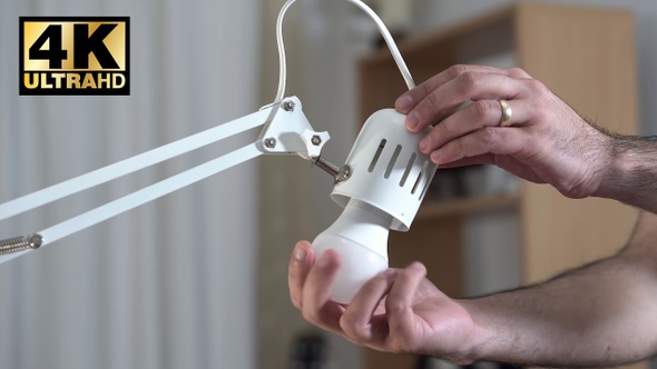 Man Replacing Old Filament Bulb With New Led Bulb 