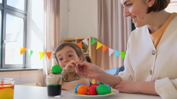 Mother with Child Dyeing Easter Eggs at Home