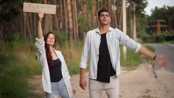 Joyful Young Man and Woman Hitchhiking with Future Banner Smiling Talking alt