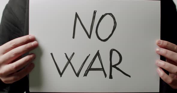 Person holding a white paper with a message No War. We Want No War Message. alt