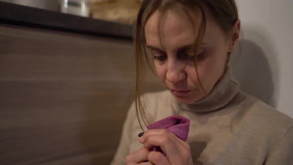 Scared Housewife in the Kitchen. Close Portrait of a Battered Woman with a Black Eye and a Split Lip alt